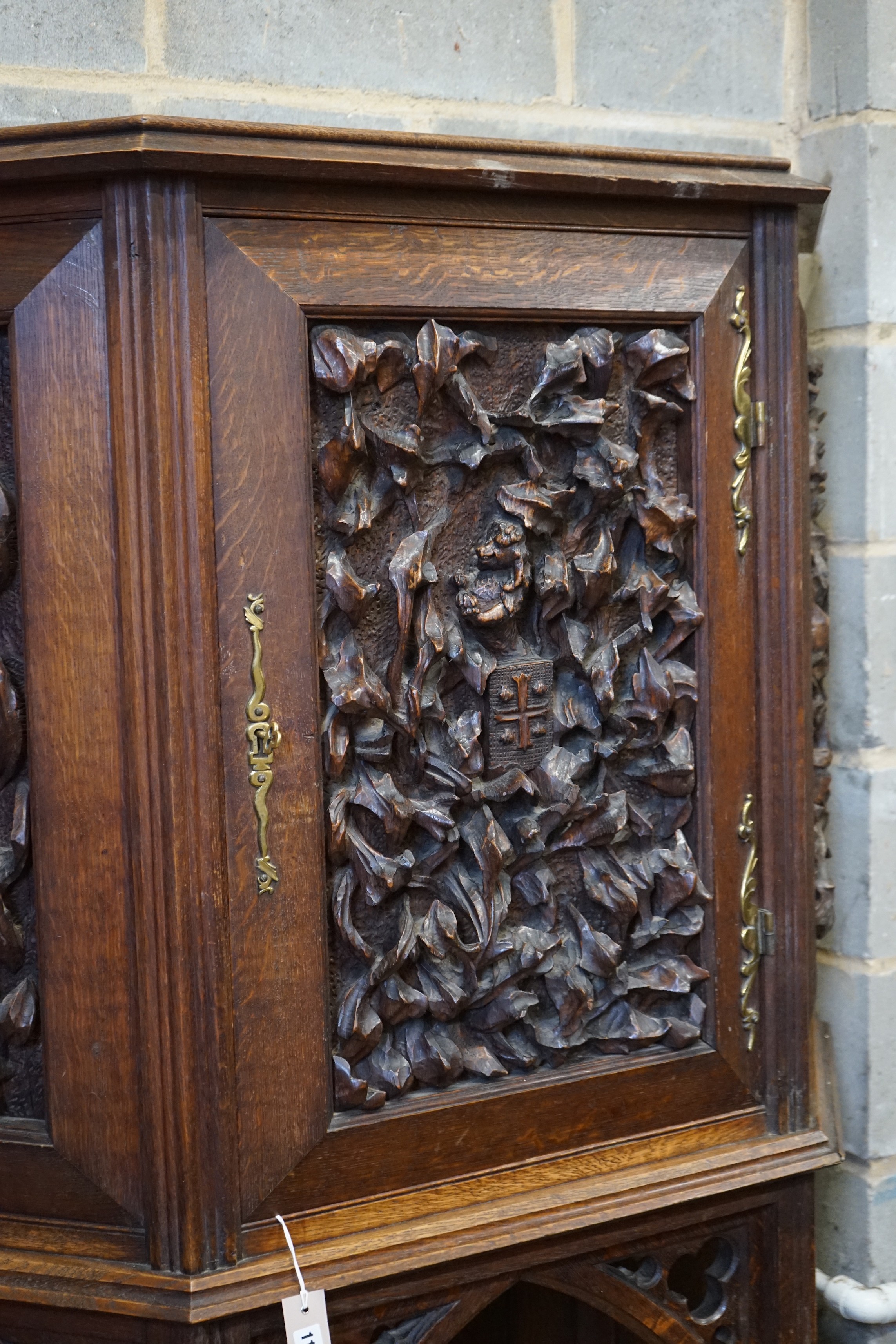 An early 20th century Gothic style carved oak side cabinet, width 118cm, depth 36cm, height 176cm